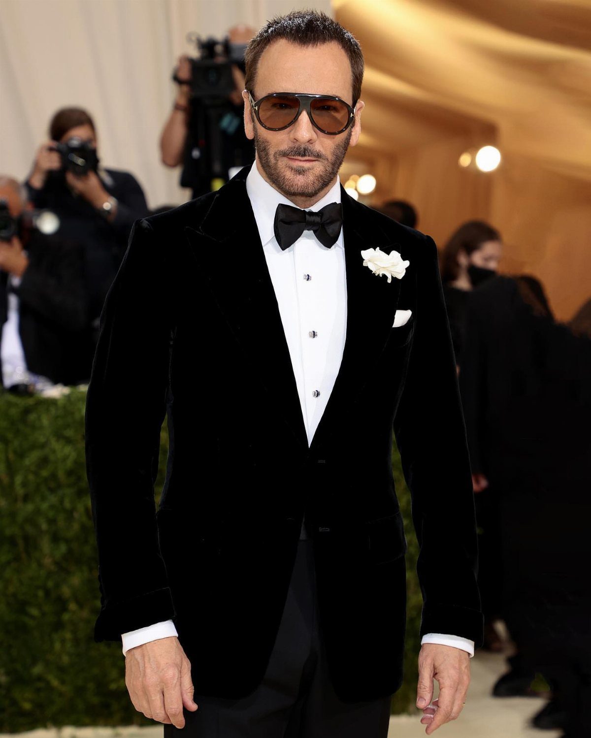 Man in a black velvet tuxedo jacket, white shirt, and black bow tie wearing sunglasses.