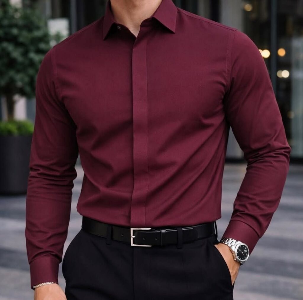 Man wearing a burgundy long-sleeved dress shirt tucked into black trousers with a silver watch.
