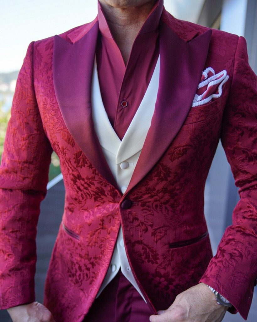 Man wearing a red floral patterned blazer with satin lapels and a cream waistcoat.