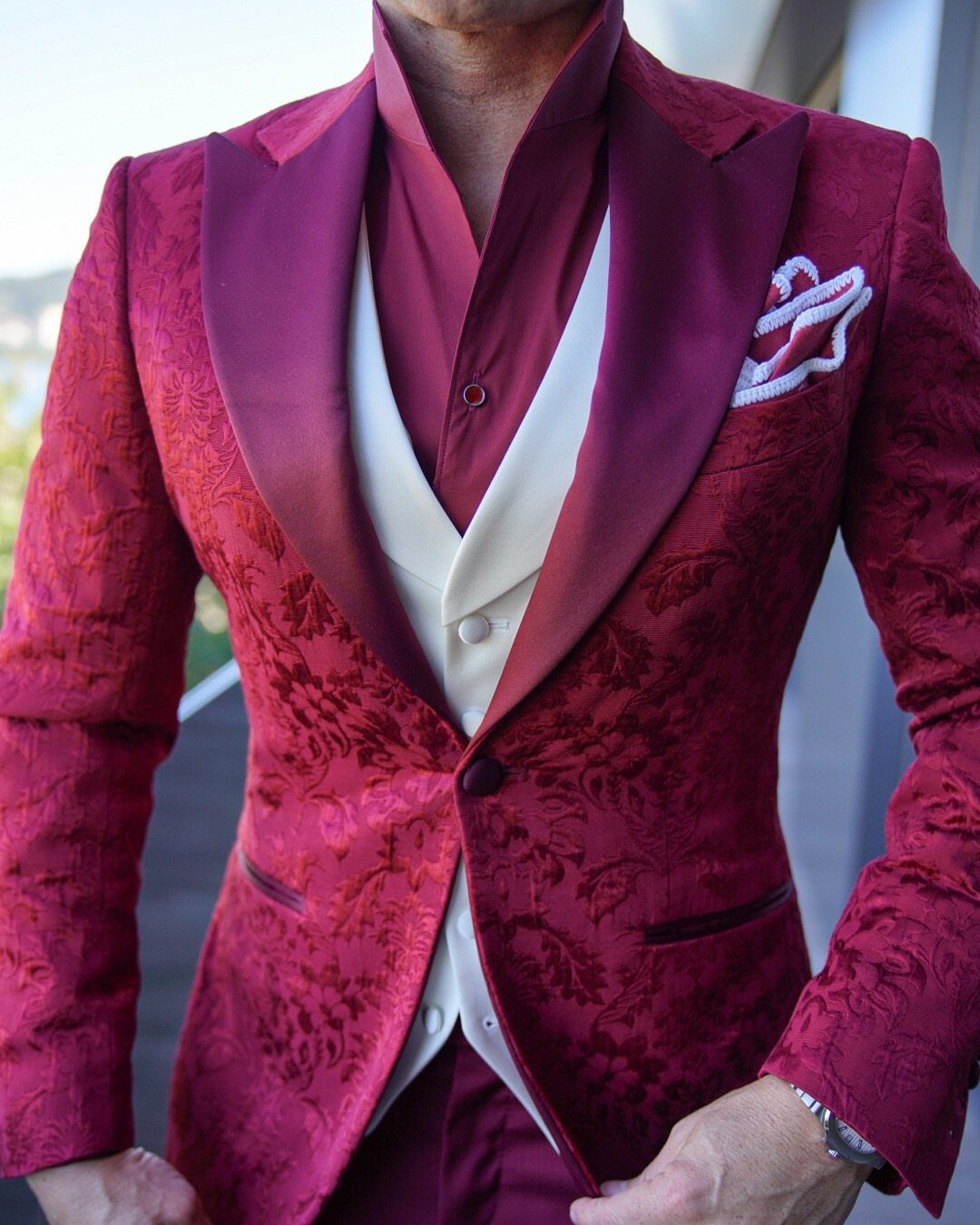 Man wearing a red floral patterned blazer with satin lapels and a cream waistcoat.
