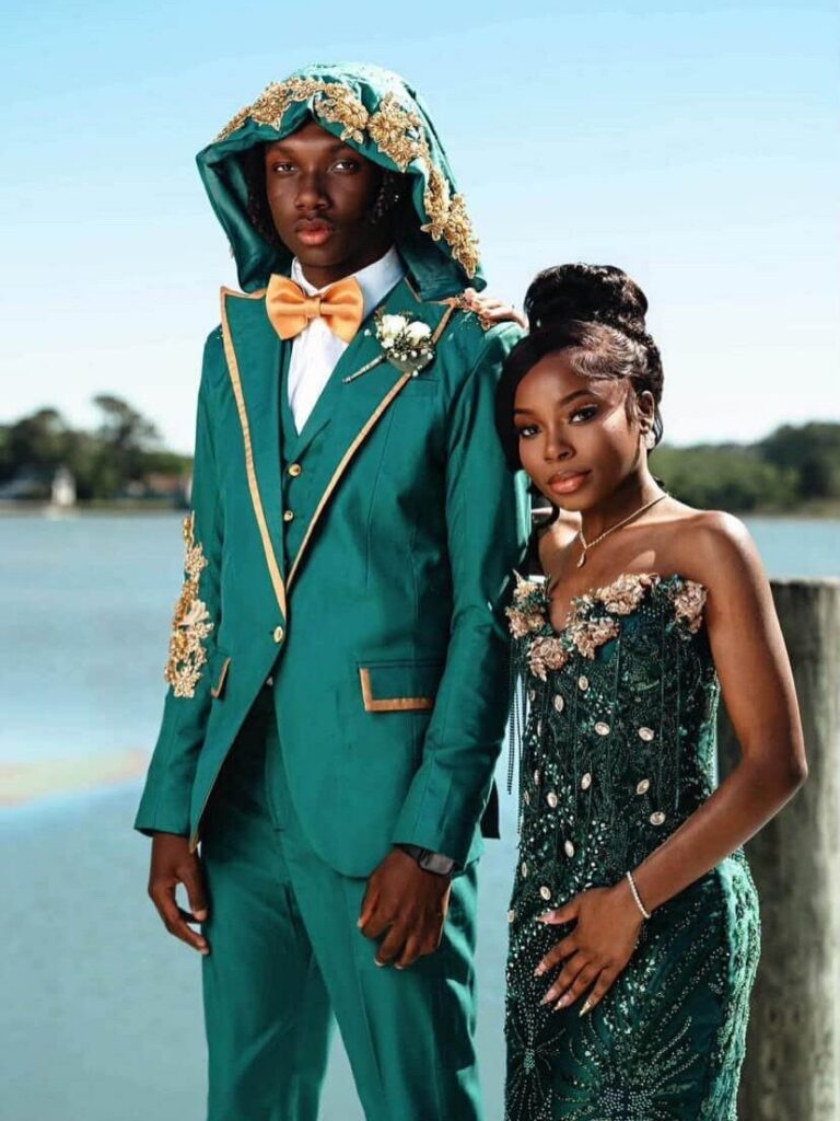 A man in a dark green embroidered three-piece suit and a woman in a green dress.