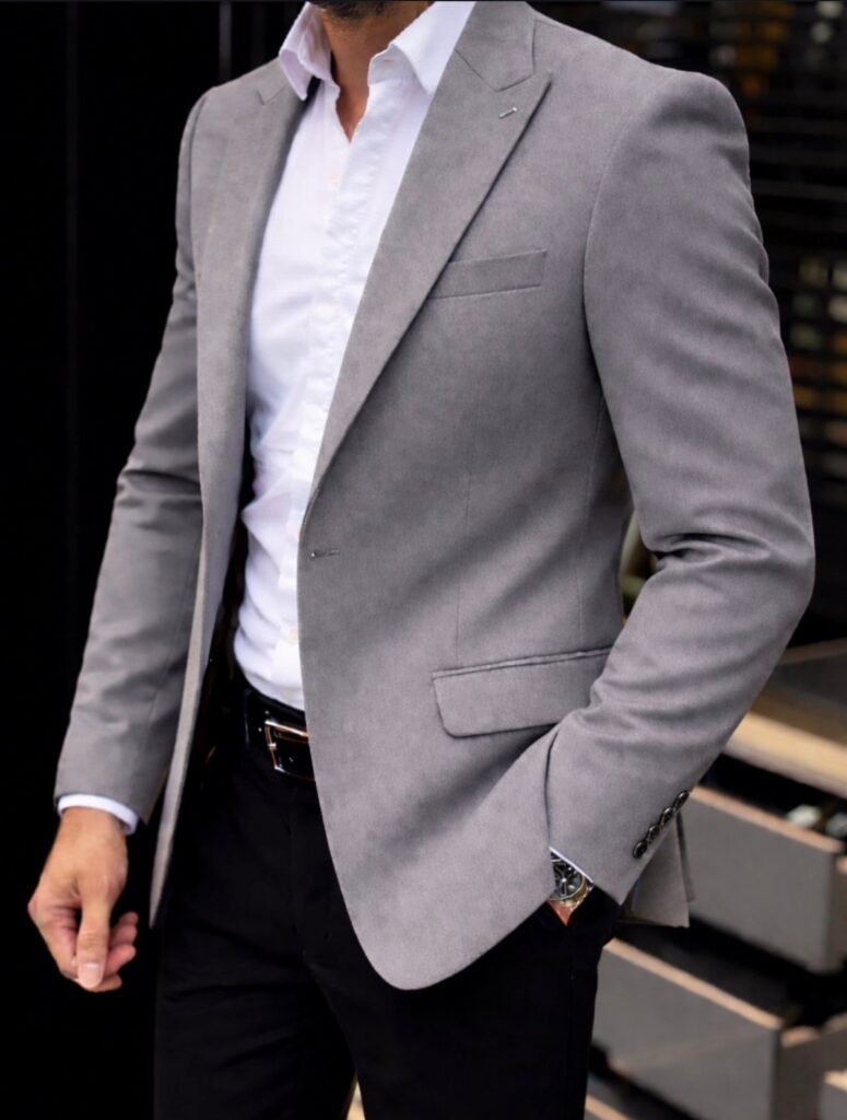 A man wearing a light grey slim fit blazer with a white shirt and black pants.