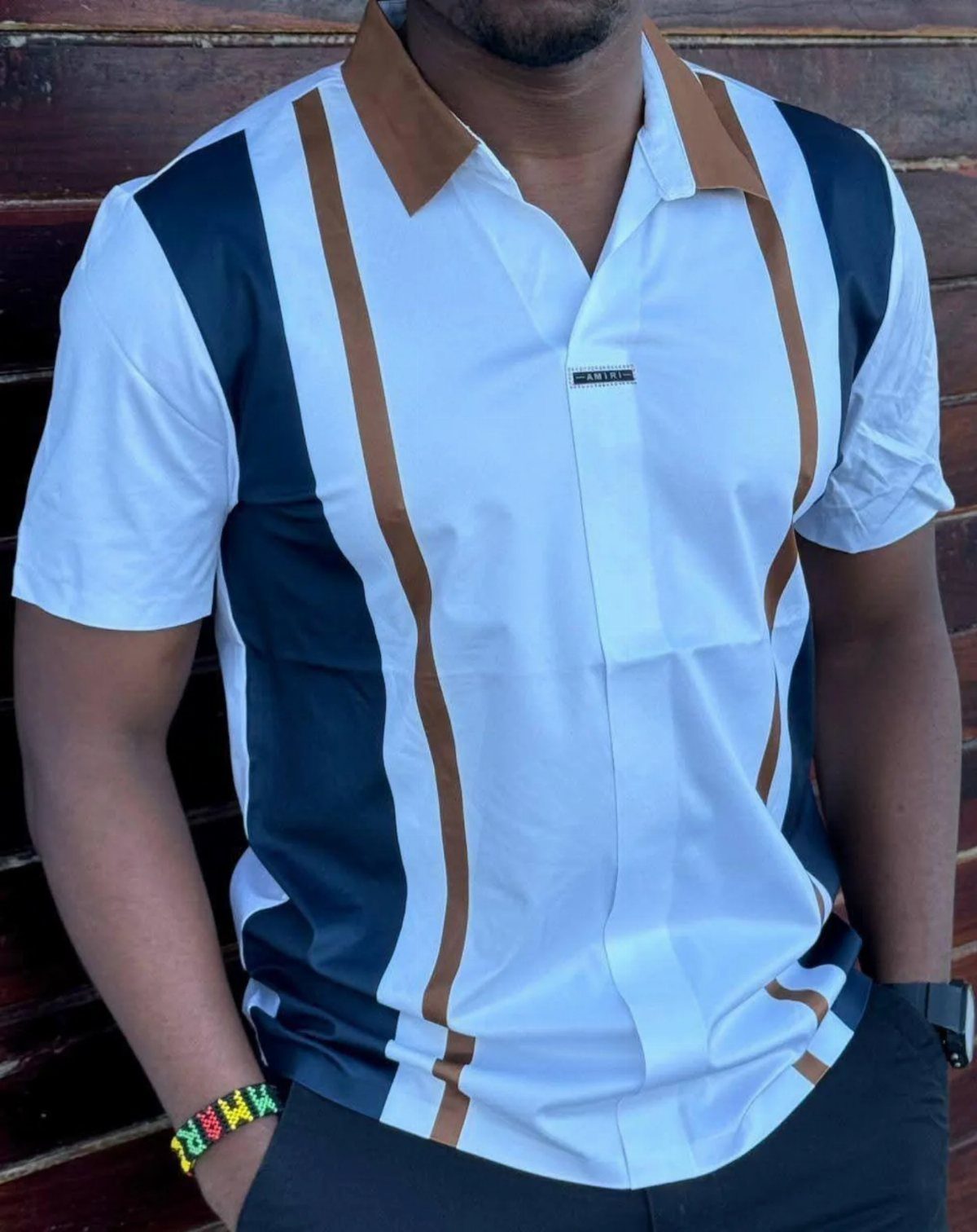 Man wearing a white short-sleeved shirt with navy and tan vertical stripes.